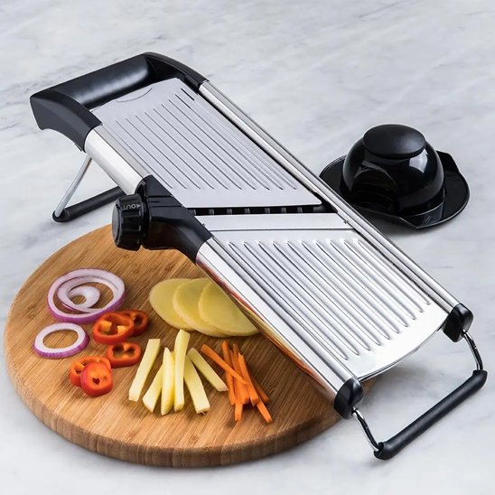 Mandoline japonaise avec accessoires et légumes tranchés sur planche bois