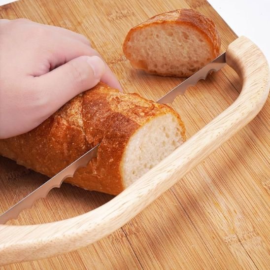 couteau à pain qui tranche du pain blanc sur une planche en bois